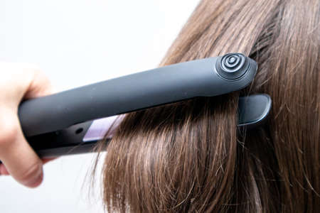 Hairstylist straightening the hair. Professional ultrasonic iron tool. Hair iron straightening. Smooth hairstyle.の写真素材