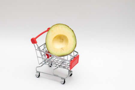 Avocado half in a shopping grocery cart. Shopping at the supermarket. Fresh vegetables and fruits