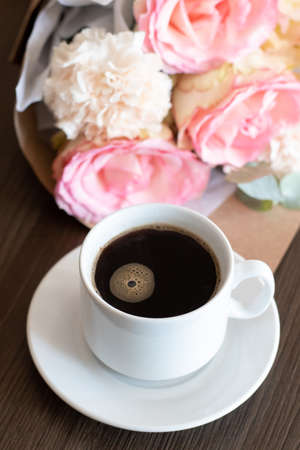 Morning Cup of coffee and a beautiful bouquet roses flowers on tableの写真素材