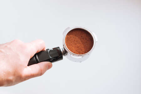Professional barista hand holding ground coffee into a portafilter for preparing.の写真素材