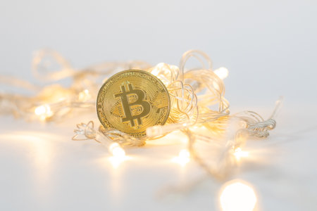 Gold bitcoin coin near yellow christmas garland. Christmas background. Digital crypto currencyの写真素材