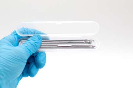 Doctor's hand in a blue glove holds a case with tools for Acne removalの写真素材