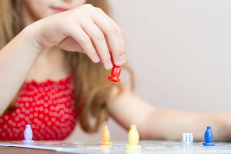 Girls hand holding a toy figure from board game, Plaing on bard game. Selective focus Board game field, many figures. Selective focus.の写真素材