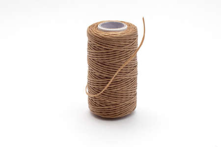 Spool of waxed brown sewing threads.