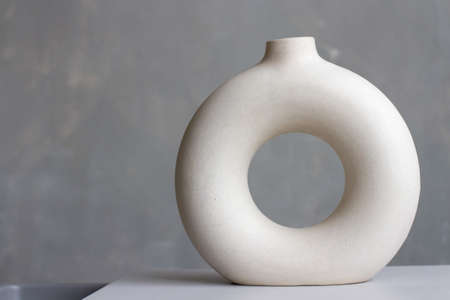 Stylish gray ceramic vase in the shape of a circle on the background of a concrete wall.の写真素材