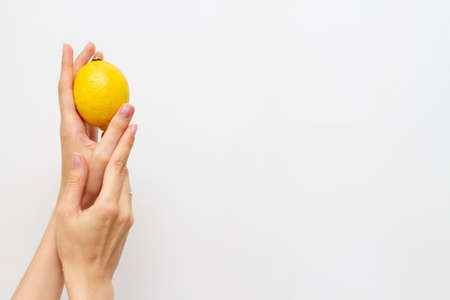 Woman hand with half of fresh lemon, free space for textの写真素材