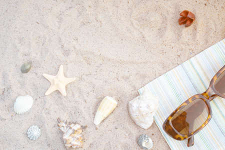 Seashells and sunglasses on the sand. Flat lay composition with vacation accessories on beachの写真素材
