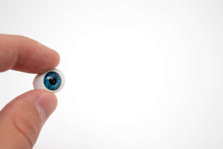 Prosthetic eyeball in hand on white background.