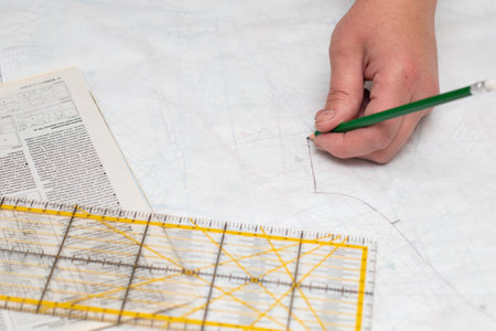 The tailor making a template. The dressmaker's hand with a pencil on the pattern and a ruler. Tailor...