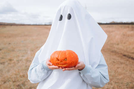 Child in Halloween costume holding carved pumpkin. Halloween trick or treatの写真素材