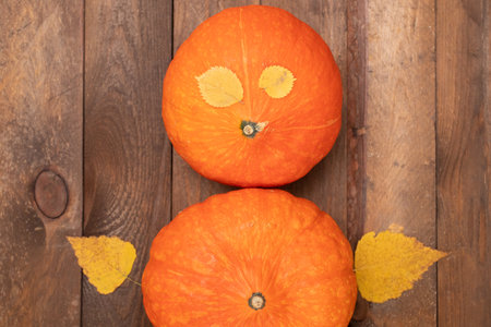 A man made of pumpkins and autumn leaves. Autumn still life on a wooden background.の写真素材