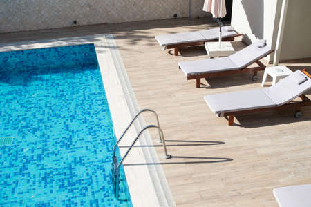 Entrance by stairs to the pool and empty sun beds