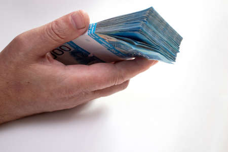 A man's hand holding a bundle of 2000 rubles bills.