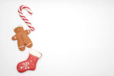 Christmas cookies in the shape of a gingerbread man, a Christmas sock and candy on a white...