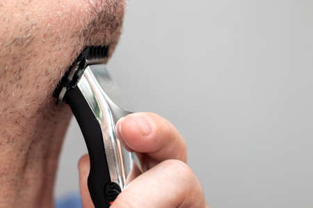 Man shaving with electric shaving machine on throat neckの写真素材