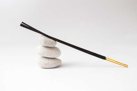 Stone and incense sticks on a white background.の写真素材