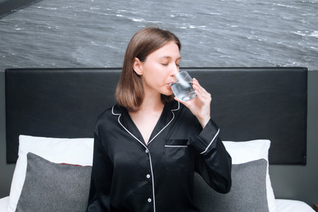 Young woman drinking water from a glass of water, closeup. Healthy lifestyle