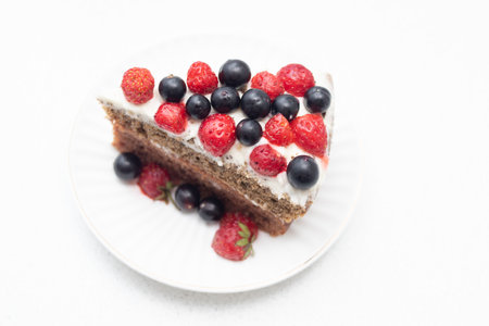 Homemade vanilla birthday cake decorated with berries: strawberries, blueberries, raspberries on plateの写真素材