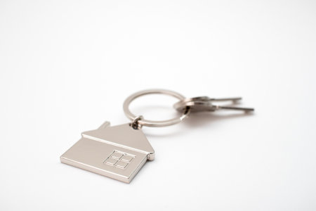 Metal key chain in the shape of a house with a metal key. real estate concept.の写真素材