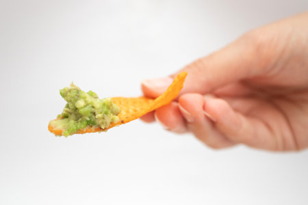 Hand with a nachos chip and guacamole dipの写真素材