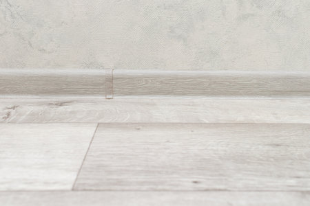 Linoleum wooden floor and plastic skirting board.