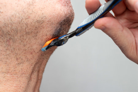 Man shaving with razor on throat neckの写真素材