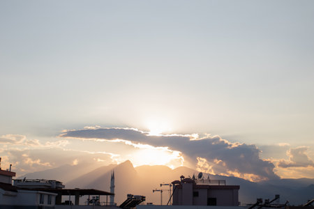 Sunset in the Turkish city of Antalya. The sun's rays break through the mountains and roofs of housesの写真素材