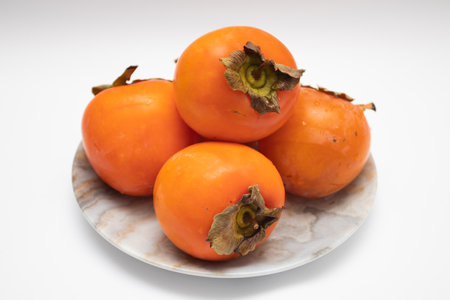 Fresh Ripe orange Persimmons on a plateの写真素材