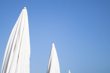 Folded umbrella on the beach against blues sky.の写真素材