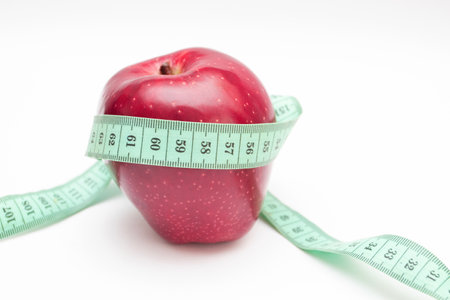 Red apple with measuring tape on white backgroundの写真素材