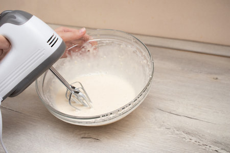 Woman kneads dough for making pancakes.の写真素材