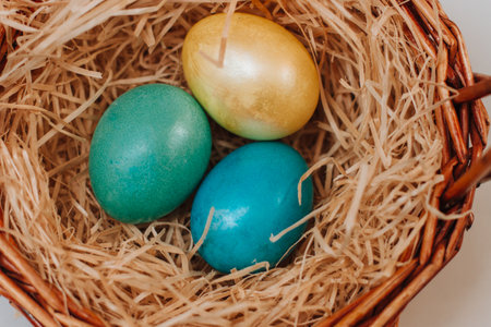 Colored easter eggs in a brown basket of twigs.の写真素材