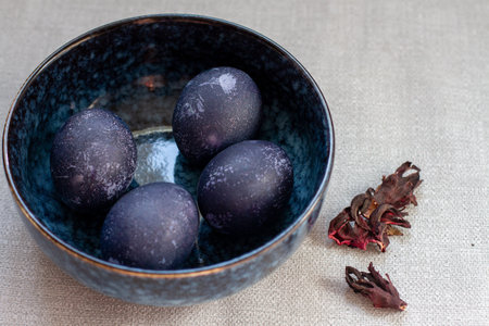 Dyed blue and marble easter eggs in a bowl with hibiscus and carcade.の写真素材
