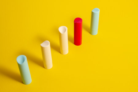 Row Multi-colored tubes of lipstick on a yellow background in an abstract shape and shapeの写真素材
