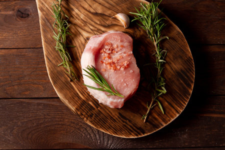Raw piece of meat on a cutting board and wooden background. top viewの写真素材