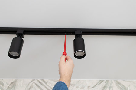 A man repairs a spot track LED light in the ceiling.の写真素材