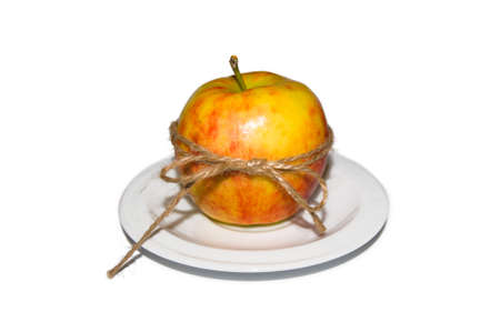 Apple tied with twine on a white plateの写真素材