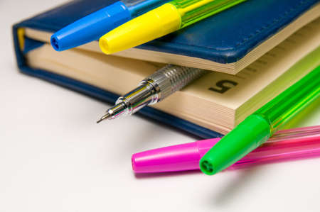 Blue diary with a silvery mechanical pencil between the pages inside and few color pens.の写真素材