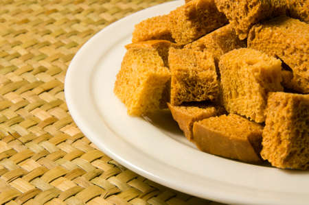 White bread high-fired croutons on white plate close-up.