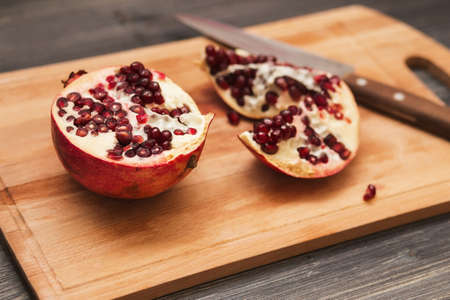 Pomegranate fruits and knife on wooden table backgroundの写真素材