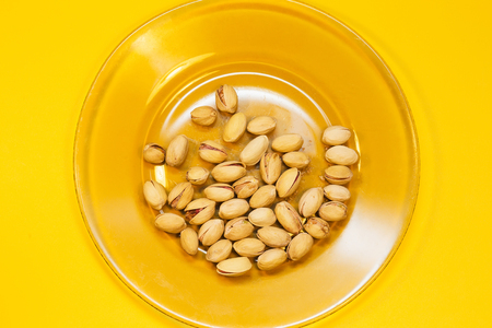Pistachio nuts on yellow background, close upの写真素材
