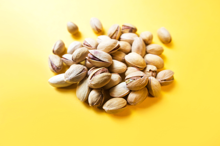 Pistachio nuts on yellow background, close upの写真素材
