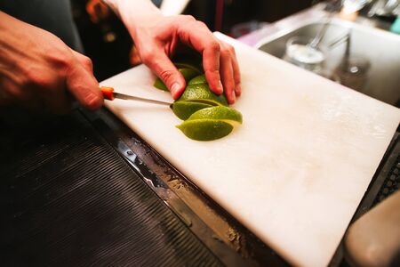 Hands with a paring knife slicing a limeの写真素材