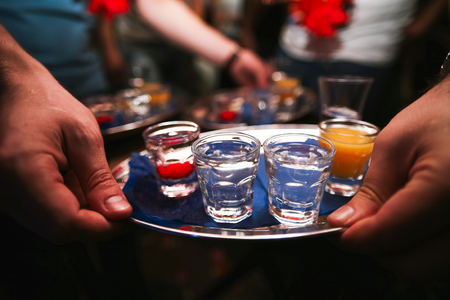 Several shot glasses on silver tray in bar setting