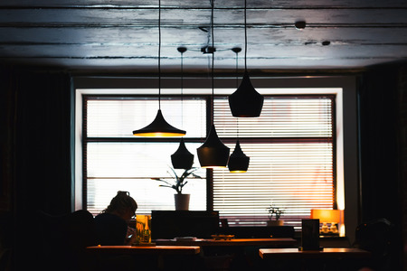 Contemporary lights illuminate the dark room. Vintage style. People rest at the table