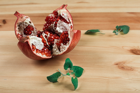 Beautiful ripe pomegranate lying on the wooden light backgroundの写真素材