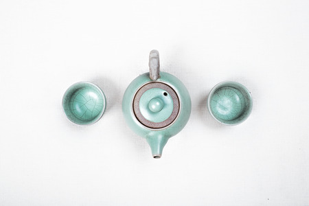 Green teapot with cups on white background.