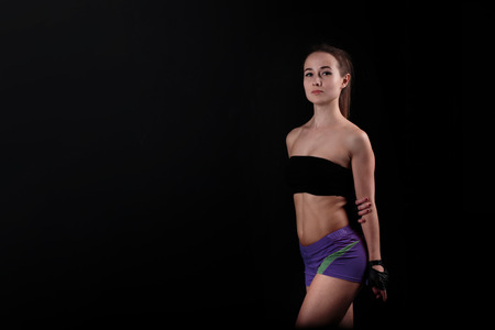 Sport girl stands and stares at the camera against a black background.の写真素材