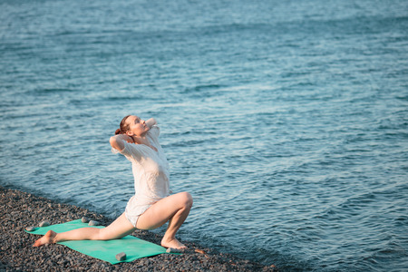 The girl is engaged in yoga on the seashore. Practicing yoga at sea.の写真素材