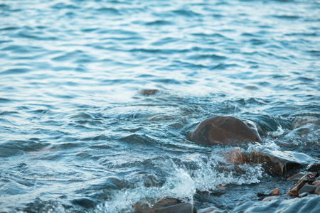 Stone beach at sunset. Sea waves on the coast.の写真素材